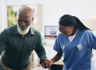 Nurse, senior man and recovery with walking in home for injury, care and holding hands with steps i